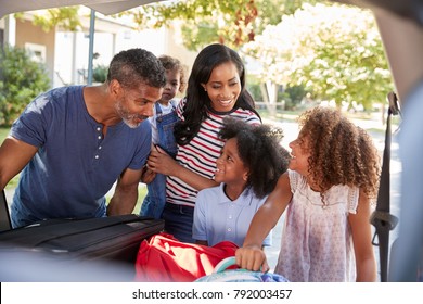 Family Leaving For Vacation Loading Luggage Into Car