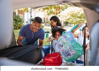 Family Leaving For Vacation Loading Luggage Into Car
