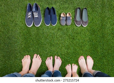 Family legs standing on green grass having fun outdoors in spring park with theirs shoes