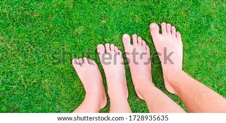 Family legs standing on green grass having fun outdoors in spring park. Close to nature, love to nature concept. Summer time. Copy space banner.