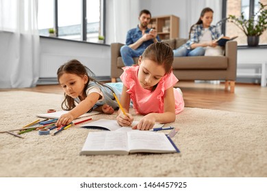 family, leisure and childhood concept - happy sisters lying on floor and drawing and doing homework at home - Powered by Shutterstock