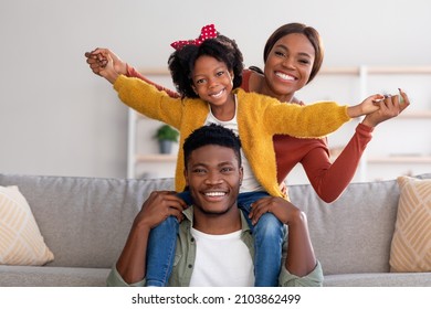 Family Leisure. Happy Black Mom, Dad And Little Daughter Having Fun At Home Together, African American Father, Mother And Cute Female Child Playing In Living Room And Smiling At Camera, Free Space