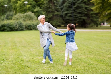 family, leisure and people concept - happy grandmother and granddaughter playing game or dancing at summer park - Powered by Shutterstock