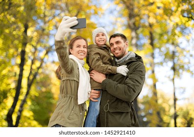 family, leisure and people concept - happy mother, father and little daughter taking selfie by smartphone over autumn park background - Powered by Shutterstock