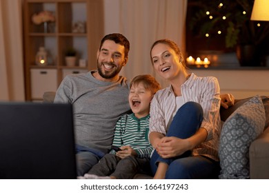 family, leisure and people concept - happy smiling father, mother and little son with remote control watching tv at home at night - Shutterstock ID 1664197243