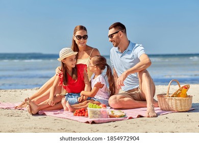 family, leisure and people concept - happy mother, father and two daughters having picnic on summer beach