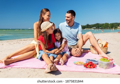 family, leisure and people concept - happy mother, father and two daughters having picnic on summer beach