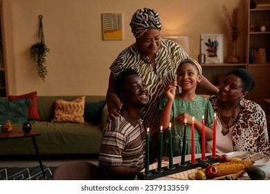 Family letting little girl to light colorful candles for Kwanzaa celebration - Powered by Shutterstock