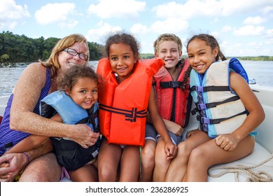 Family In Life Jackets On A Boat On A Lake