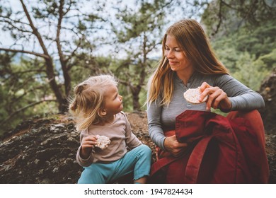 Family lifestyle mother and daughter child outdoor in forest on picnic eating rice cookies travel vacations together with kid 