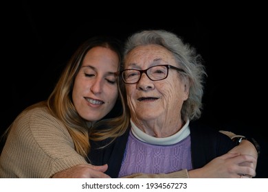 Family Lifestyle Portrait Of Elderly 80s Woman Hugging Young Grand Daughter