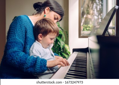 Family lifestyle spending time together indoors. Children with musical virtue and artistic curiosity. Educational musical activities for little kid. Mom teaching her son at home piano lessons.