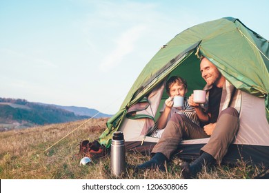 Family lisure concept image. Father and son drink a tea sitting in touristic tent - Powered by Shutterstock