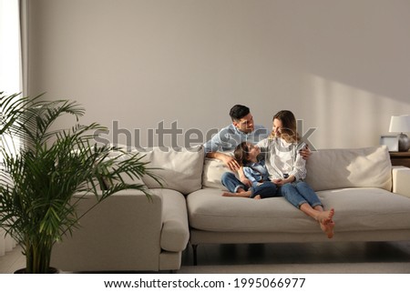 Family with little daughter resting on sofa in living room