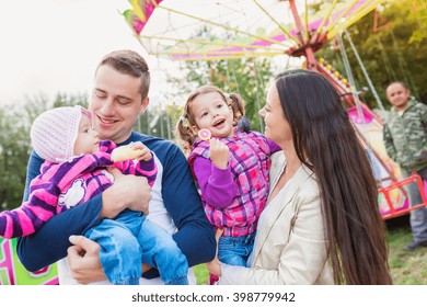 Family With Little Girls Enjoying Time At Fun Fair