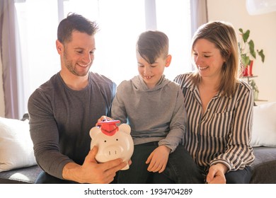 A Family With Little Son With Piggy Bank At Home