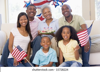 Family In Living Room On Fourth Of July With Flags And Cookies Smiling