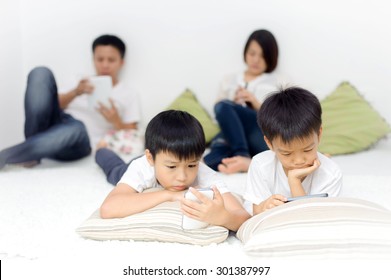 Family In Living Room Using Smartphone And Tablet Device Each One Separately. Social Network Concept.