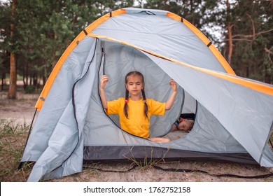 Family Local Getaway. Kid Sitting In The Camping Tent At Campsite And Looking At Sunset, Healthy Active Lifestyle, Safe Summer Staycation After Lockdown