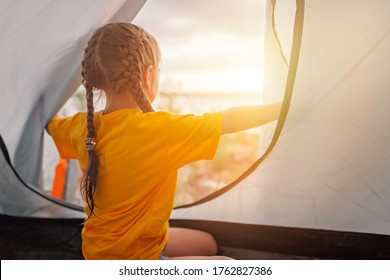 Family Local Getaway. Kid Sitting In The Camping Tent At Campsite And Looking At Sunset, Healthy Active Lifestyle, Safe Summer Staycation After Lockdown