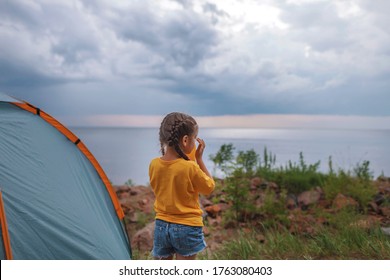 Family Local Getaway. Kid Sitting In The Camping Tent At Campsite And Looking At Sunset, Healthy Active Lifestyle, Safe Summer Staycation After Lockdown