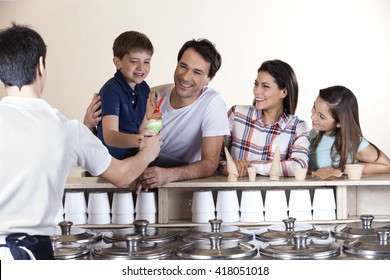 Family Looking At Boy While Waiter Serving Him Ice Cream