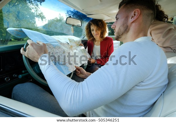 Family looking at map on tablet and roadmap\
while travel by car during\
holidays