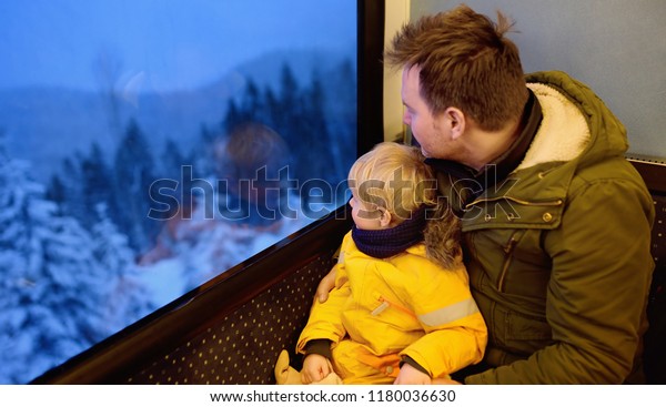 Family looking out of the\
window of train during travel on cogwheel railway/rack railway in\
Alps mountains. Winter holidays in Swiss/German/Italian\
Alps