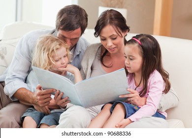 Family Looking At A Photo Album In The Living Room