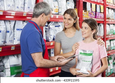 Family Looking At Salesman Using Digital Tablet In Pet Store