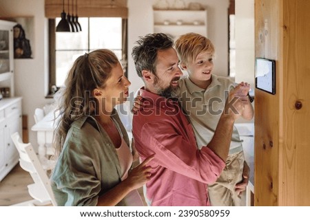 Family looking at smart thermostat, adjusting, lowering heating temperature at home. Concept of sustainable, efficient, and smart technology in home heating and thermostats.