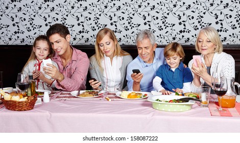 Family Looking At Their Smartphones At The Dinner Table