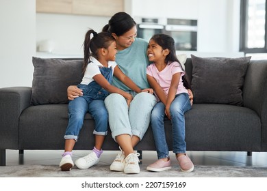 Family, Love And Single Mother With Kids Looking Happy, Relax And Smiling Sitting Together And Bonding On Sofa In Lounge At Home. Asian Babysitter Woman Hugging Cute Girls, Daughters Or Twin Sisters