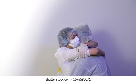 Family loving husband and wife. Man in a protective suit, safety glasses, medical mask and cute female doctor woman in a protective mask hug and express romantic feelings. Coronavirus or COVID-19.