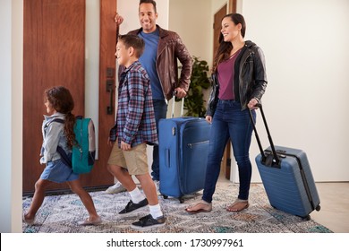 Family With Luggage Opening Door And Leaving Home For Vacation