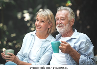 Family Lunch Outdoor. Couple Of White Senior Man And Woman Sitting And Smiling Together In Tropical Garden.