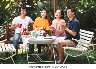 Family Lunch Outdoor. Married Mix Race Couple With Grand Parents. White Man, Asian Pregnant Woman With Senior Asian Couple In Tropical Garden. Having Fun.