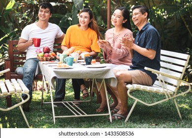 Family Lunch Outdoor. Married Mix Race Couple With Grand Parents. White Man, Asian Pregnant Woman With Senior Asian Couple In Tropical Garden. Enjoying Conversation Together.