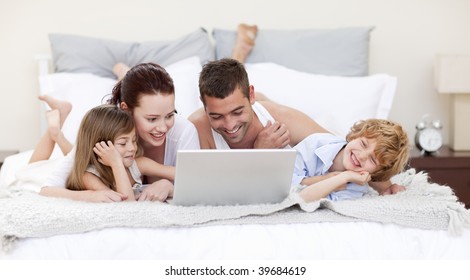 Family lying in bed using a laptop - Powered by Shutterstock