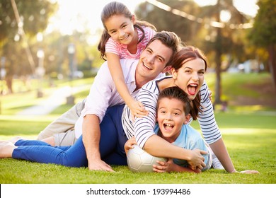 Family Lying On Grass In Park Together