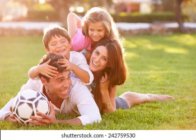 Family Lying In Pile Up On Grass Together