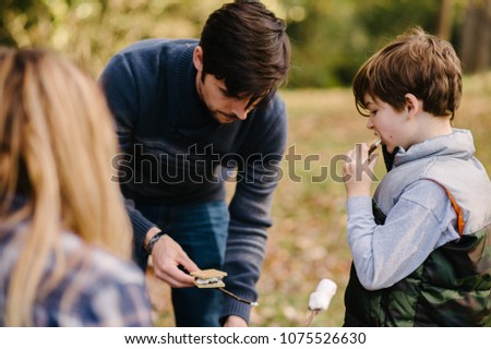 Family making marshmallow s'mores on camping trip	