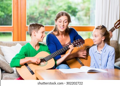 Family making music at home with guitar, mother, daughter and son playing