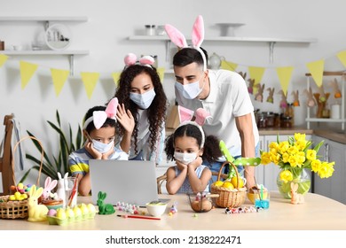 Family With Medical Masks Video Chatting In Kitchen On Easter Day