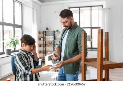 Family, Medicine And Health Concept - Father Healing Son's Injured Finger With Antiseptic At Home