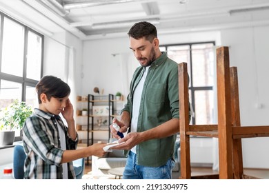 Family, Medicine And Health Concept - Father Healing Son's Injured Finger With Antiseptic At Home