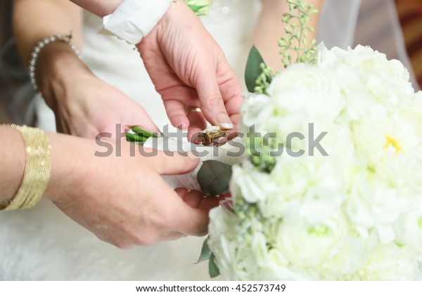 Family member places good luck charm or\
something borrowed on brides\
bouquet.