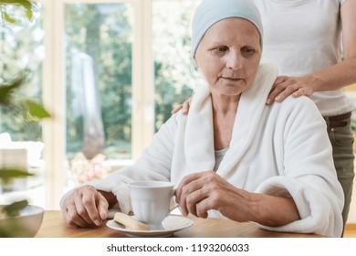 Family Member Supporting Sick Elderly Woman With Cancer While Drinking Tea