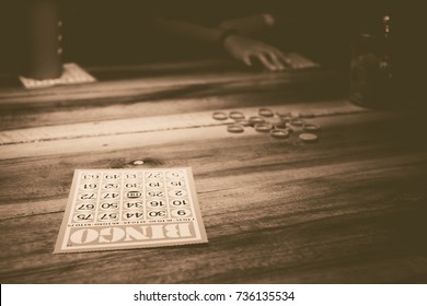 Family Members Come Together Playing Bingo During A Holiday. The Vintage Bingo Card On Wooden Table.  A Game Of Chance, Each Player Matches Numbers Pre-printed In Different Arrangements On 5×5 Cards.