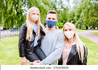 Family Members Embracing Each Other, Smiling In The Camera Wearing Cloth Face Masks. Father, Mother And Daughter Protect Themselves From The Virus.